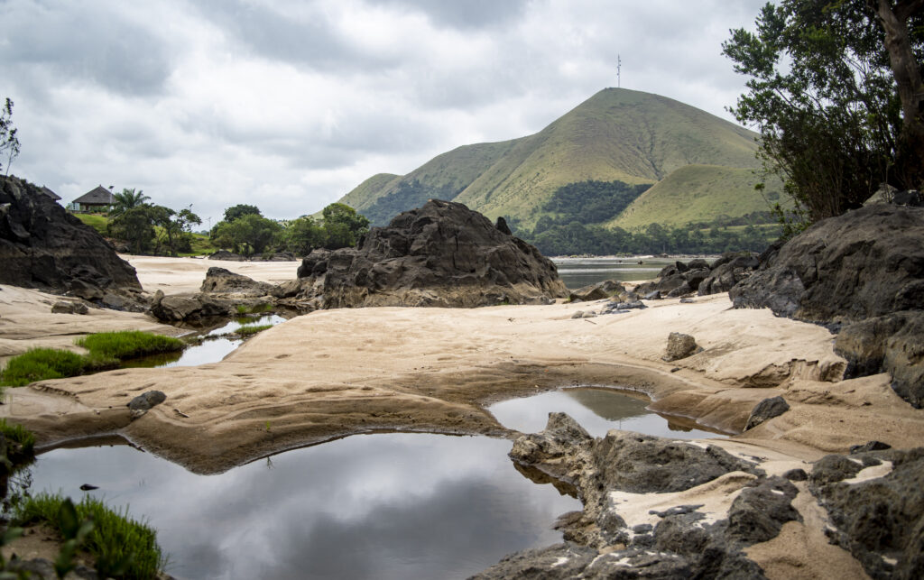 Plage de sable, rochers et mont vert
